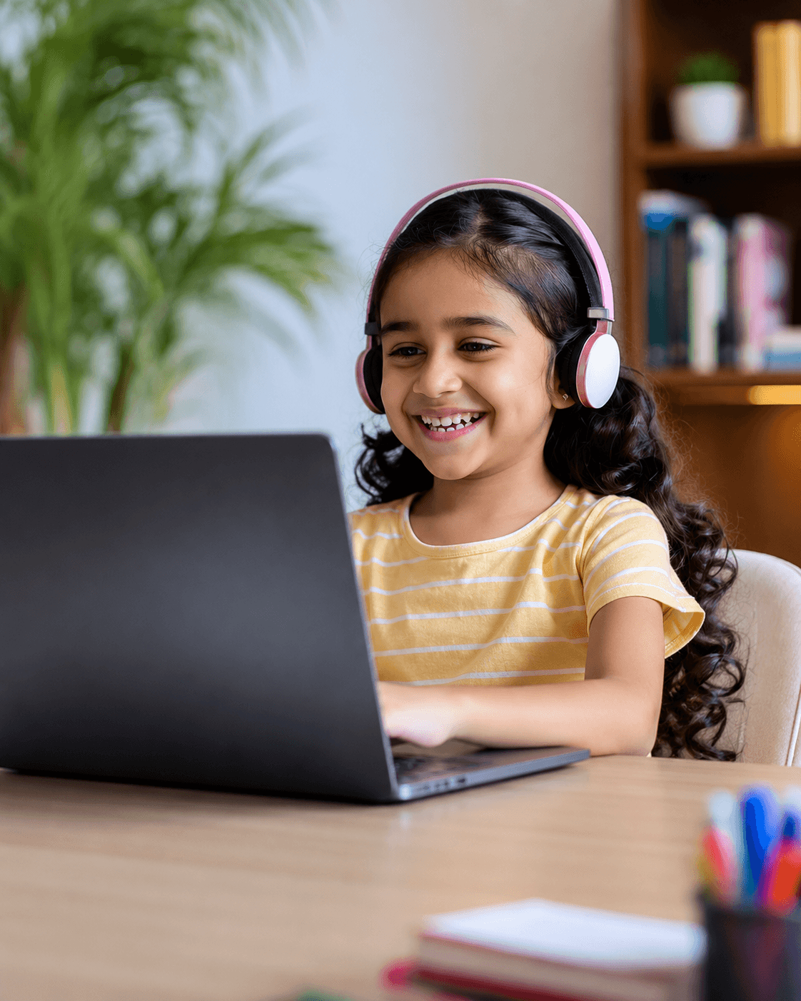 A happy young SpikiTech learner wearing headphones, smiling while studying on a laptop