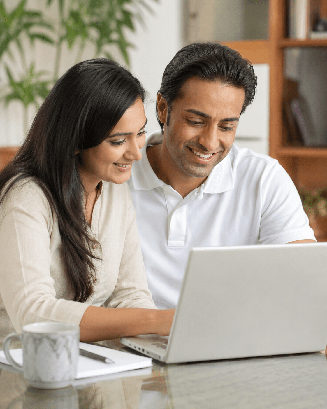 Two parents happily reviewing their child’s learning progress together on a laptop